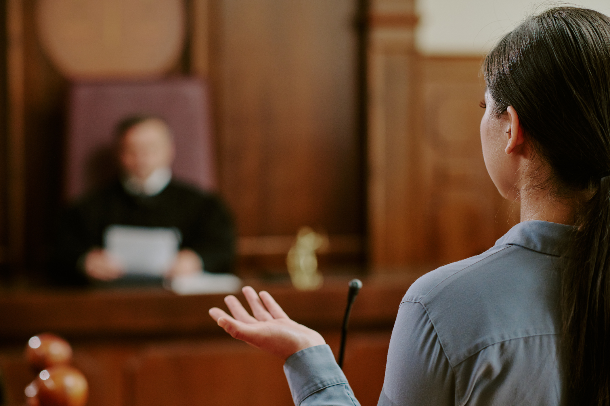 Back of women standing in front of a judge giving a deposition